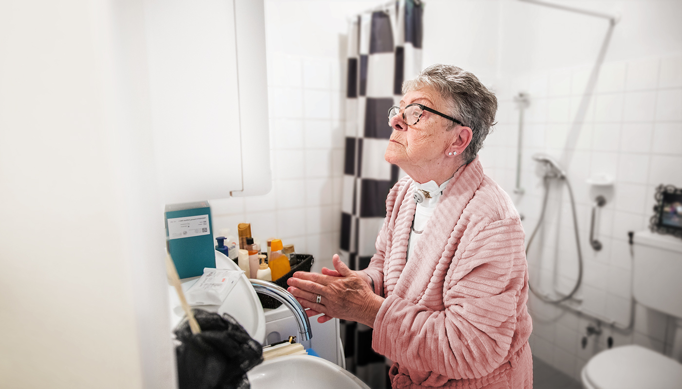 Woman caring for tracheostomy in bathroom